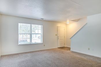 a bedroom with a large window and carpeted floor